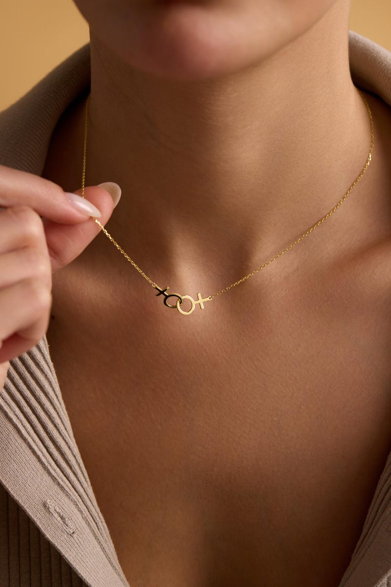 May include: A gold chain necklace with a pendant featuring a circle with a cross on either side.
