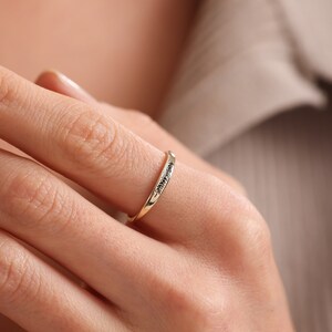 Puede incluir: Un fino anillo de banda de oro con una fila de peque&ntilde;os diamantes negros.