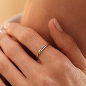 Puede incluir: Un fino anillo de banda de oro con una fila de peque&ntilde;os diamantes negros.