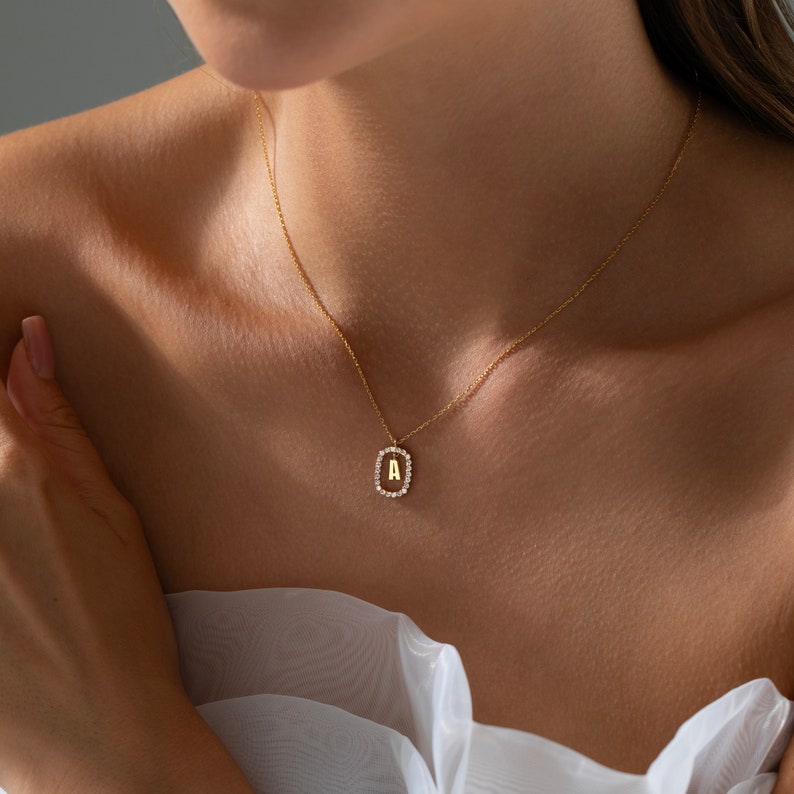 K&ouml;nnte beinhalten: Eine goldene Halskette mit einem diamantbesetzten Anh&auml;nger mit dem Buchstaben 'A'.