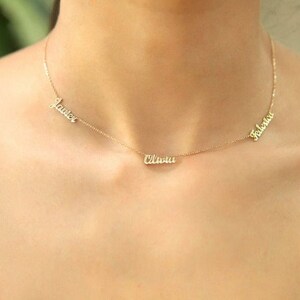 May include: A gold necklace with three names on it: "Lauren", "Olivia", and "Fabiana".