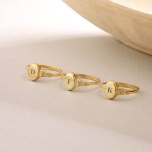 May include: Three gold rings with oval-shaped tops. Each ring has a different initial engraved on the top: D, F, and K.