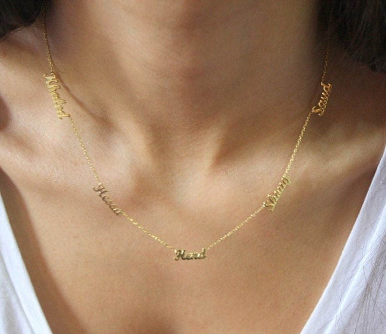 May include: A gold chain necklace with five names on it: "Maxwell", "Hena", "Hend", "Sherry", and "Saud".
