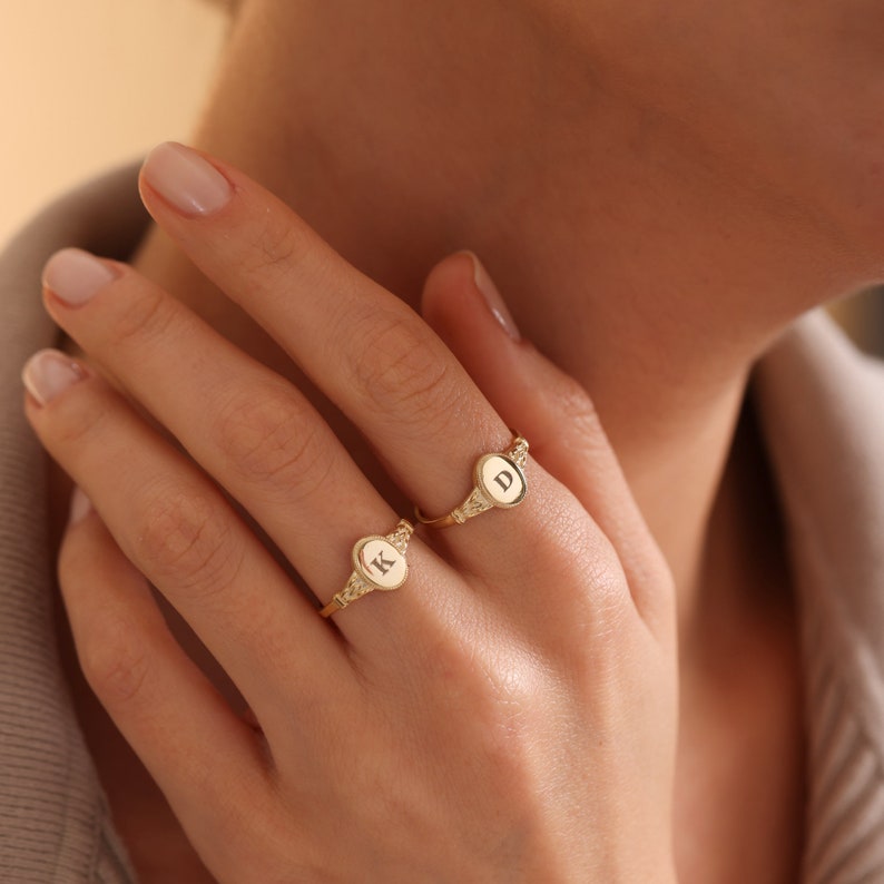 May include: Two gold rings with oval-shaped tops. The tops of the rings are engraved with the letters "K" and "D".