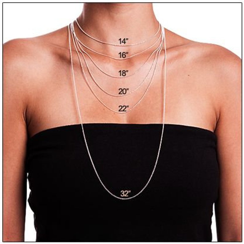 May include: A model wears a silver chain necklace in various lengths, from 14 inches to 32 inches. The necklace is shown on a person with a black top.