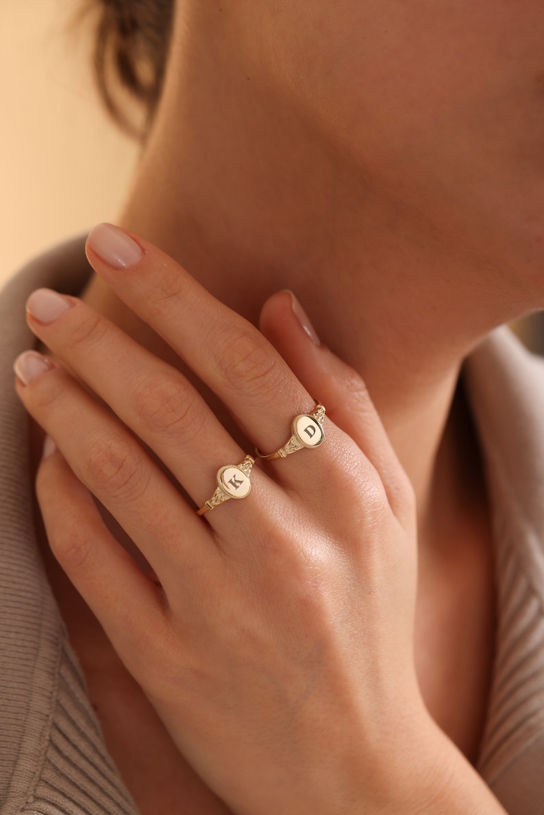 May include: Two gold rings with oval-shaped tops. The rings are engraved with the letters "K" and "D".