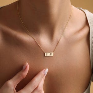 K&ouml;nnte beinhalten: Eine goldene Halskette mit einem rechteckigen Anh&auml;nger, auf dem "11:11" steht.