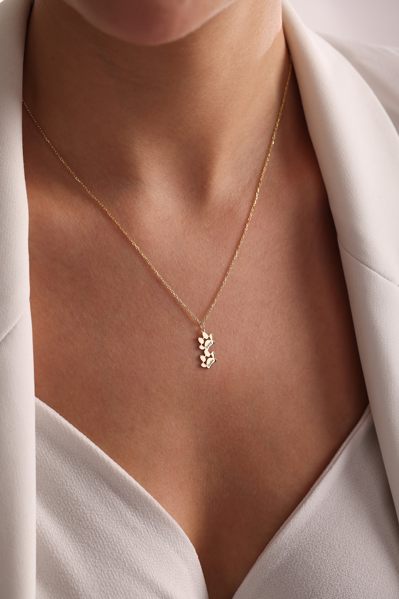 May include: A gold chain necklace with a small pendant featuring a cluster of stylized leaves.