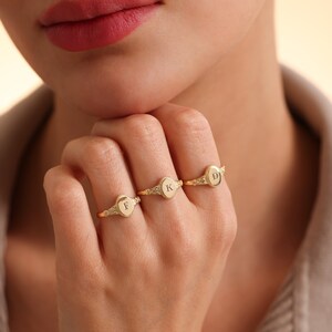 May include: Three gold signet rings with the letters F, K, and D engraved on the oval tops.