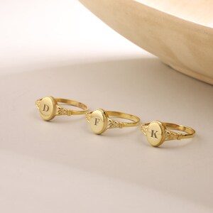May include: Three gold rings with oval-shaped tops. The tops are engraved with the letters D, F, and K.