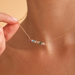 Puede incluir: Un collar de cadena dorada con un colgante de piedras preciosas de colores. El colgante presenta un grupo de peque&ntilde;as piedras preciosas rectangulares en tonos de rosa, azul, verde y blanco.