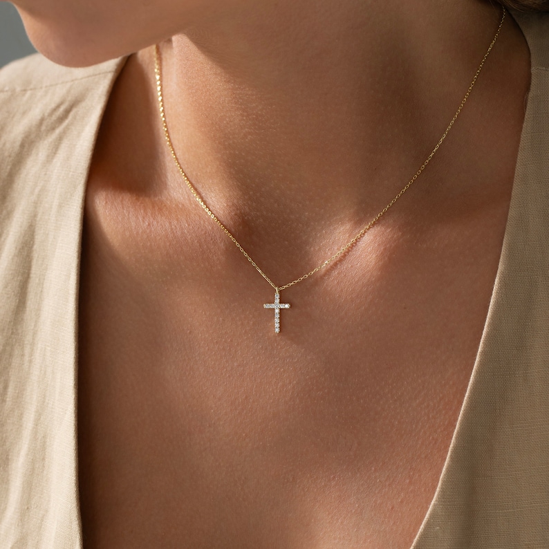 K&ouml;nnte beinhalten: Eine goldene Kettenkette mit einem kleinen, mit Diamanten besetzten Kreuzanh&auml;nger.