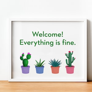 May include: White framed print with the text "Welcome! Everything is fine." and four potted cacti in different colors. The cacti are green with pink flowers.
