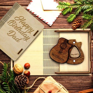 Könnte beinhalten: Eine Holzkiste mit einem Gitarrenplektrum und einer Gitarrenform darin. Die Kiste ist mit den Worten "Happy Birthday Dad" und "William" graviert.