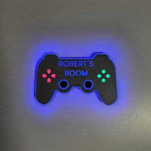 May include: A black and blue illuminated game controller with the text "ROBERT'S ROOM" on it.