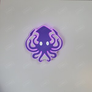 May include: A purple and white octopus wall decoration with a light purple glow. The octopus has two large white eyes and eight tentacles.