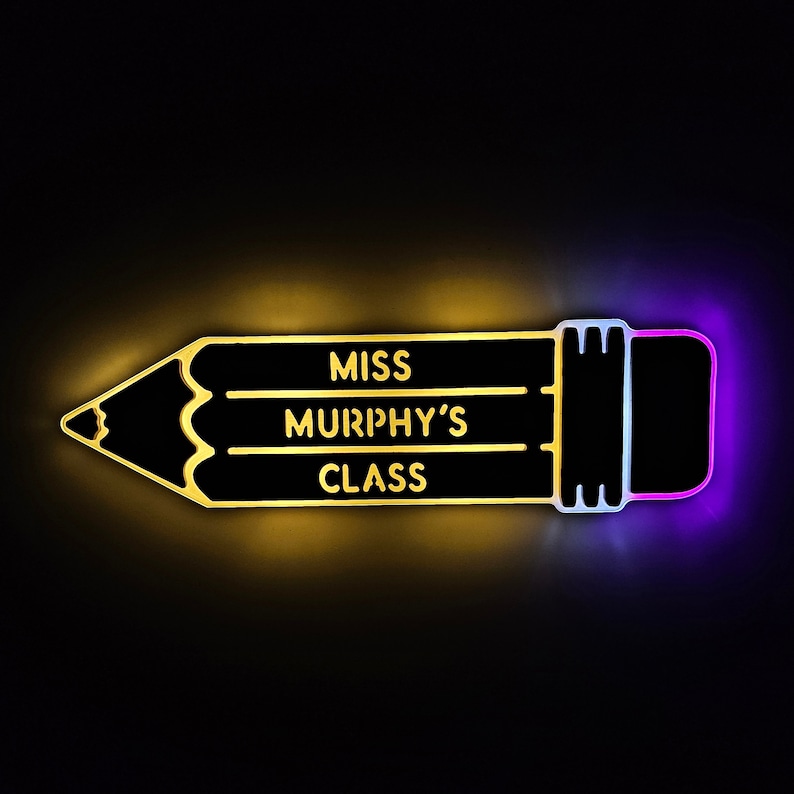 K&ouml;nnte beinhalten: Ein schwarzes schildf&ouml;rmiges Schild in Form eines Bleistifts mit gelber und violetter Beleuchtung. Das Schild tr&auml;gt die Aufschrift "Miss Murphy's Class".