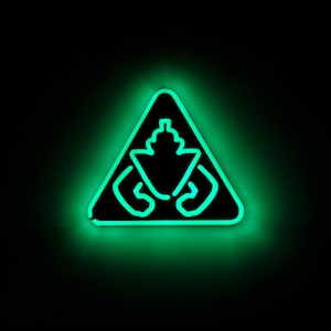 Puede incluir: Un letrero de neón verde en forma de triángulo con una figura estilizada en su interior. La figura es negra y tiene una cabeza redondeada con una parte superior puntiaguda y dos brazos doblados en los codos.