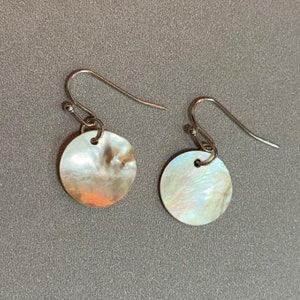 May include: A pair of silver earrings with round iridescent white and brown shell accents.