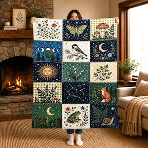 Peut inclure: Une courtepointe rectangulaire composée d'une grille de quinze panneaux illustrant des motifs naturels tels qu'un papillon de nuit, des champignons, un oiseau, un soleil, un renard, une grenouille, un escargot, des constellations, des fougères et des phases lunaires dans des tons bleu marine, vert et crème.