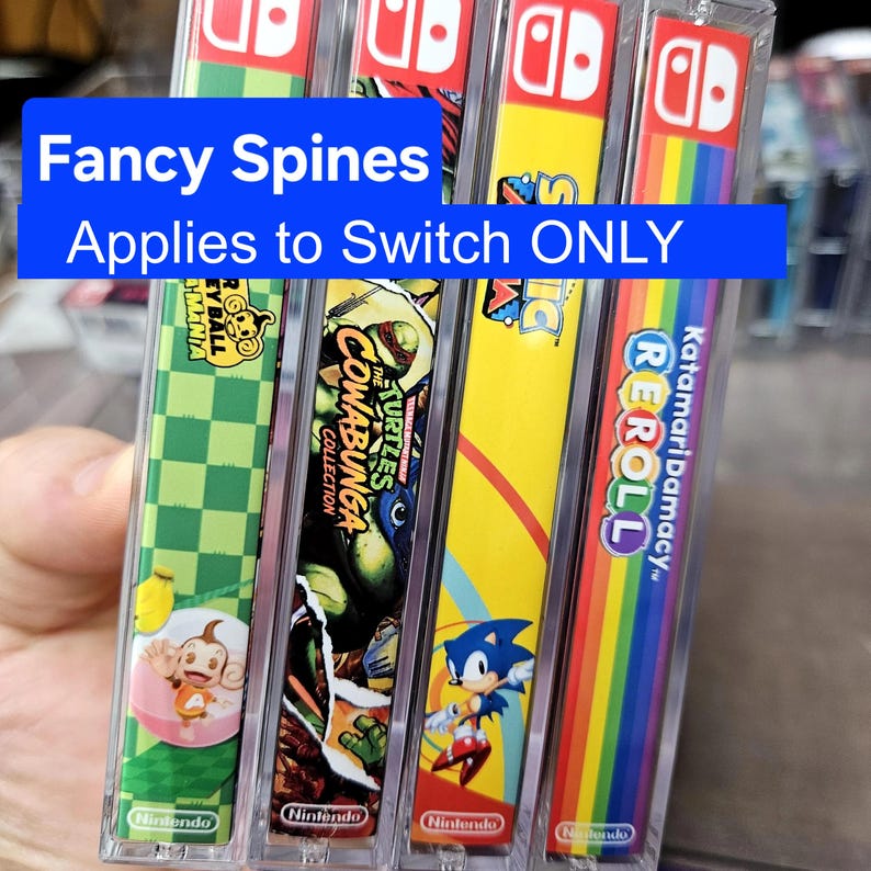 May include: Four Nintendo Switch game cartridges with colorful spines. The games are "Katamari Damacy Reroll", "Sonic Mania", "Teenage Mutant Ninja Turtles: Cowabunga Collection", and "Super Mario Odyssey".