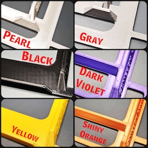 May include: Close-up of five different colored plastic frames. The colors are pearl, gray, black, dark violet, and yellow. The frames are all the same size and shape.