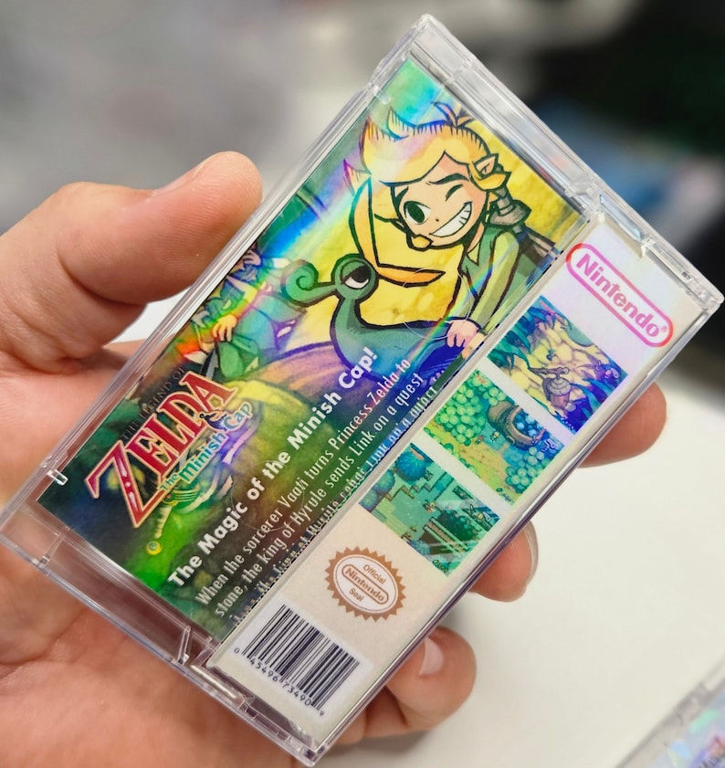 May include: A clear plastic case with a holographic image of Link from The Legend of Zelda: The Minish Cap video game. The back of the case features a description of the game, the Nintendo logo, and a barcode.