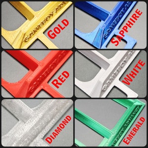 May include: Five 3D printed game cartridge holders in different colors: gold, red, white, diamond, and emerald. Each holder has the text "GAMEBOY ADVANCE" printed on it.