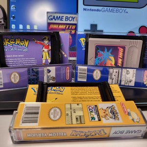 May include: Three Game Boy cartridges in protective cases. The cartridges are for Pokemon Gold & Silver, Pokemon Yellow Version, and a game called 'Jungle Heat'.