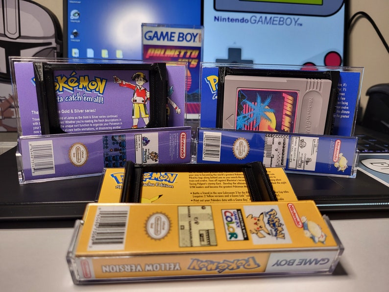May include: Three Game Boy cartridges in protective cases. The cartridges are for Pokemon Gold & Silver, Pokemon Yellow Version, and a game called 'Jungle Heat'.