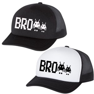 May include: Two trucker hats, one black and one white, each with a black brim and mesh back. The hats feature the word "BRO" in white pixelated letters, followed by two pixelated alien figures.