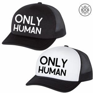 May include: Two trucker hats with black mesh backs. One hat is black with white text that says "ONLY HUMAN". The other hat is white with black text that says "ONLY HUMAN".