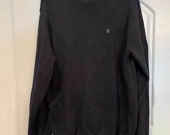 May include: Black sweater with a diamond pattern and a small logo on the left chest. The sweater has long sleeves and a crew neck.