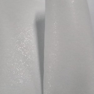 Puede incluir: Dos piezas de tela blanca con una superficie texturizada. La tela tiene un brillo sutil.