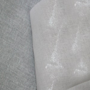 May include: Two pieces of white fabric, one with a smooth texture and the other with a slightly rougher texture. The fabric with the smooth texture has a subtle shimmer. The fabric is labeled "Wefab, Smartest Choice for Apparels (A Unit of a p y Group)".