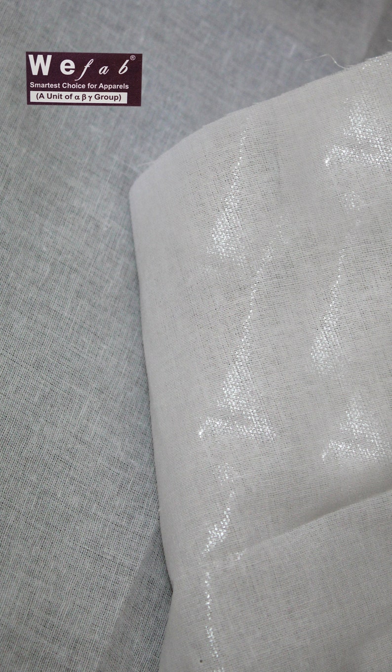 May include: Two pieces of white fabric, one with a smooth texture and the other with a slightly rougher texture. The fabric with the smooth texture has a subtle shimmer. The fabric is labeled "Wefab, Smartest Choice for Apparels (A Unit of a p y Group)".