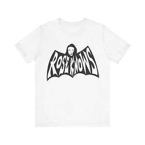 May include: White t-shirt featuring a black graphic of a bat with the text "ROSE KNOWS" inside. The bat has a woman's face in the centre.