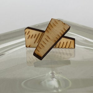 May include: Two wooden pieces with a decorative pattern, resembling a ruler or measuring tool. The pieces are light brown and have a natural wood finish.