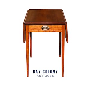 May include: A mahogany drop leaf table with a single drawer and brass hardware. The table is on a white background.
