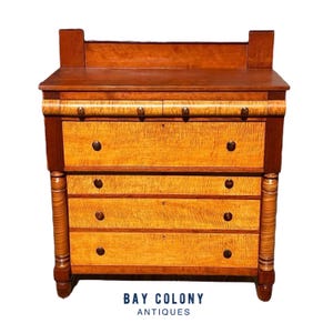 May include: Antique four-drawer chest of drawers with a wood top and a wood base. The drawers are made of wood with a light brown finish and have brass knobs. The chest is in good condition and has a classic design.