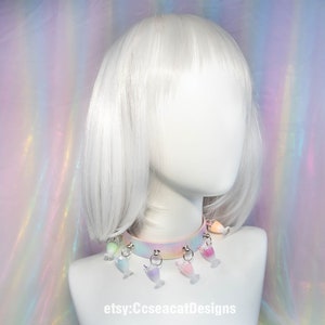 May include: A pastel rainbow choker with a white base and silver rings. The choker has multiple charms hanging from it, each charm is a different colour and shaped like a glass of juice. The text "etsy:CcseacatDesigns" is visible at the bottom of the image.