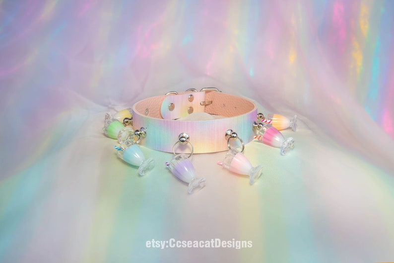 May include: A pastel rainbow coloured leather choker with silver metal accents and multiple dangling charms shaped like colourful milkshakes. etsy:CcseacatDesigns