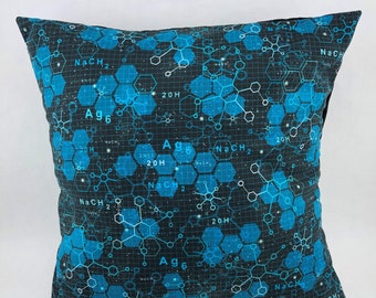 May include: A black and blue throw pillow with a geometric pattern of hexagons and chemical formulas. The formulas include NaCH2, 20H, and Ag6.