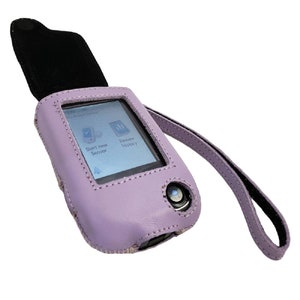 May include: A lavender leather case with a black strap for a small electronic device. The device's screen shows the words "Start new Sensor" and "Review History".