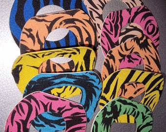 Può includere: Una collezione di toppe in tessuto colorate e decorate. Ogni toppa presenta un esclusivo motivo a strisce di tigre in vari colori, tra cui blu, arancione, rosa, giallo e verde. Le toppe hanno una forma ovale con un ritaglio circolare al centro.