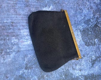 May include: A black fabric clutch bag with a gold-coloured frame. The frame is decorated with small, sparkling details. A delicate chain is attached to the frame. The bag is likely for carrying small items.