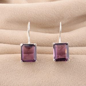 Może przedstawiać: Para srebrnych kolczyków wiszących z prostokątnymi fioletowymi kamieniami szlachetnymi.