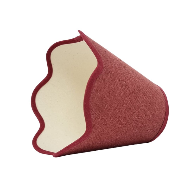 May include: A burgundy lampshade with a scalloped edge and a white lining. The lampshade is made of a textured fabric.