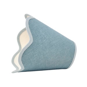 May include: A blue lampshade with a scalloped edge and a white lining. The lampshade is made of a textured fabric.