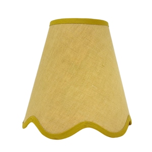 May include: A yellow lampshade with a scalloped edge and a yellow trim.